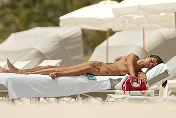 Italian actress Manuela Arcuri sunbathing topless on a beach